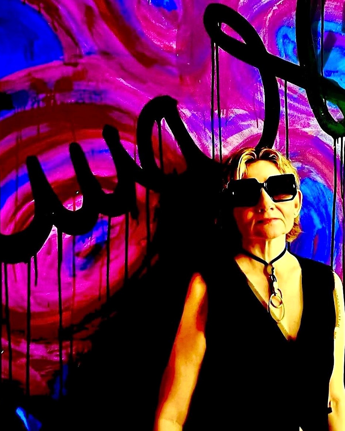 Ana Vélez frente a una de sus obras, con lentes oscuros y vestida de negro